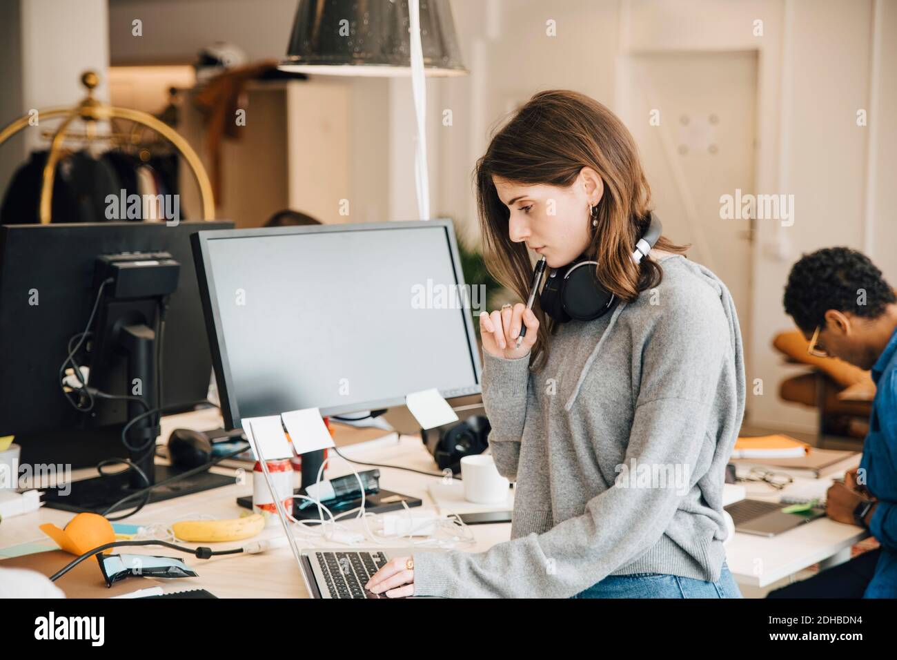 Female computer programmer analyzing data on laptop at desk in office Stock Photo