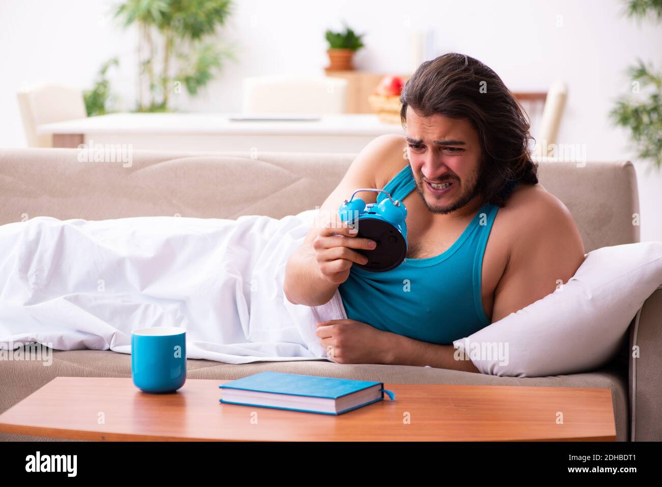 Young man lying on the sofa in time management concept Stock Photo Alamy