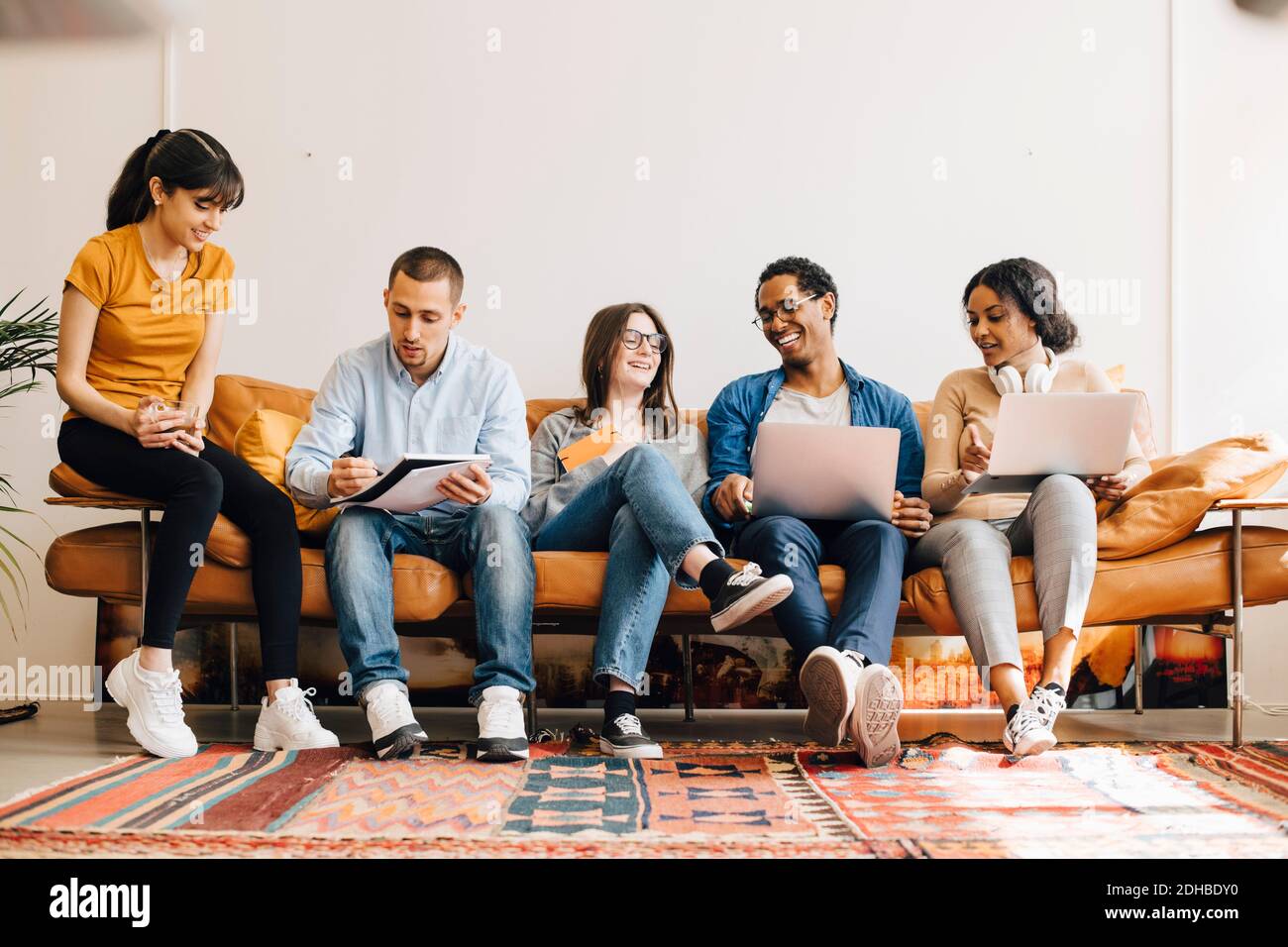 Happy colleagues working together while sitting on sofa in creative office Stock Photo