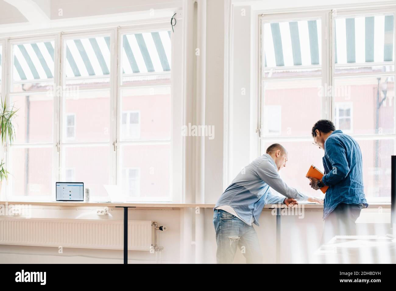 Male computer programmers discussing at desk by window in office Stock Photo