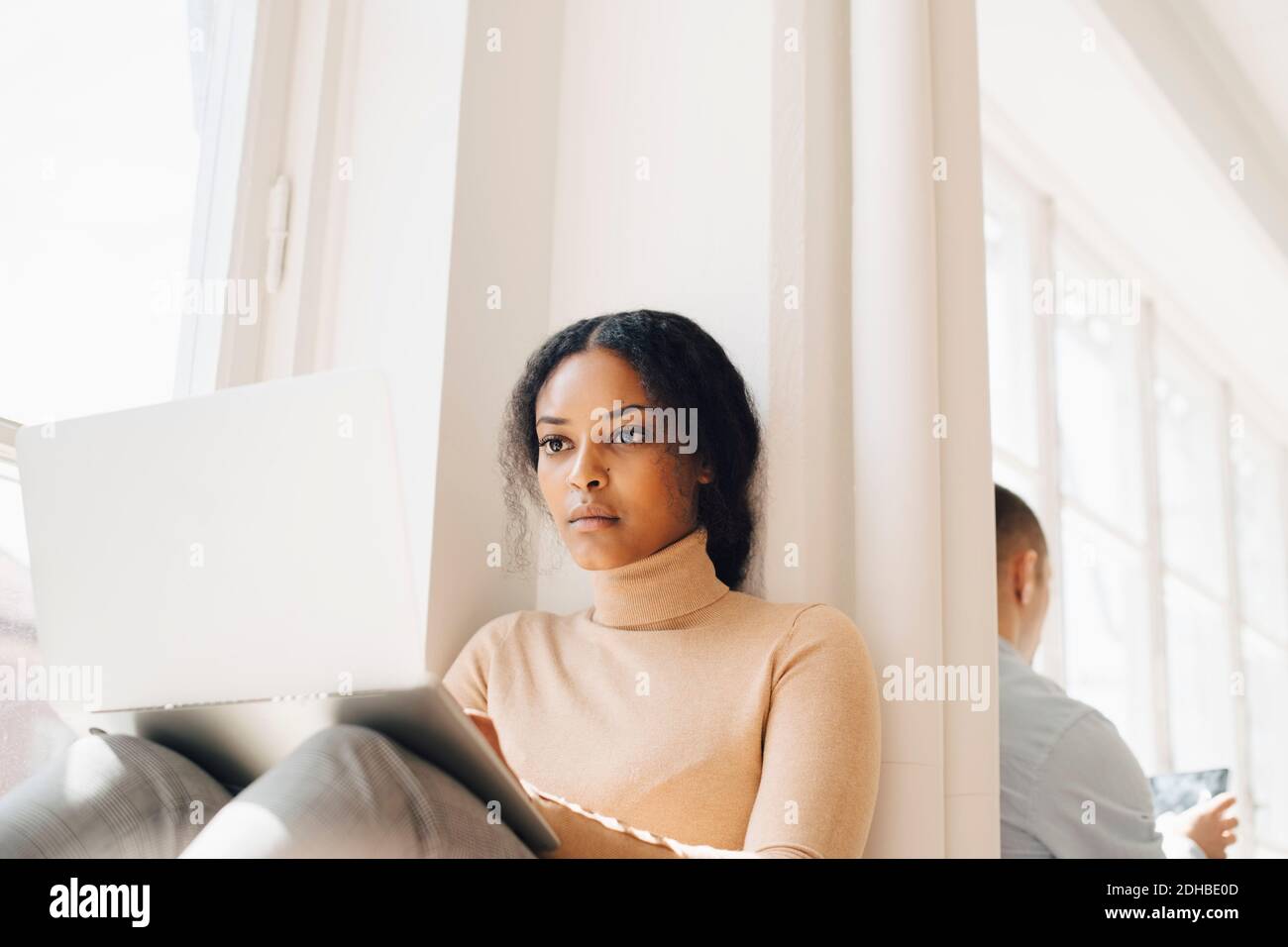 IT programmer using technologies by window in office Stock Photo
