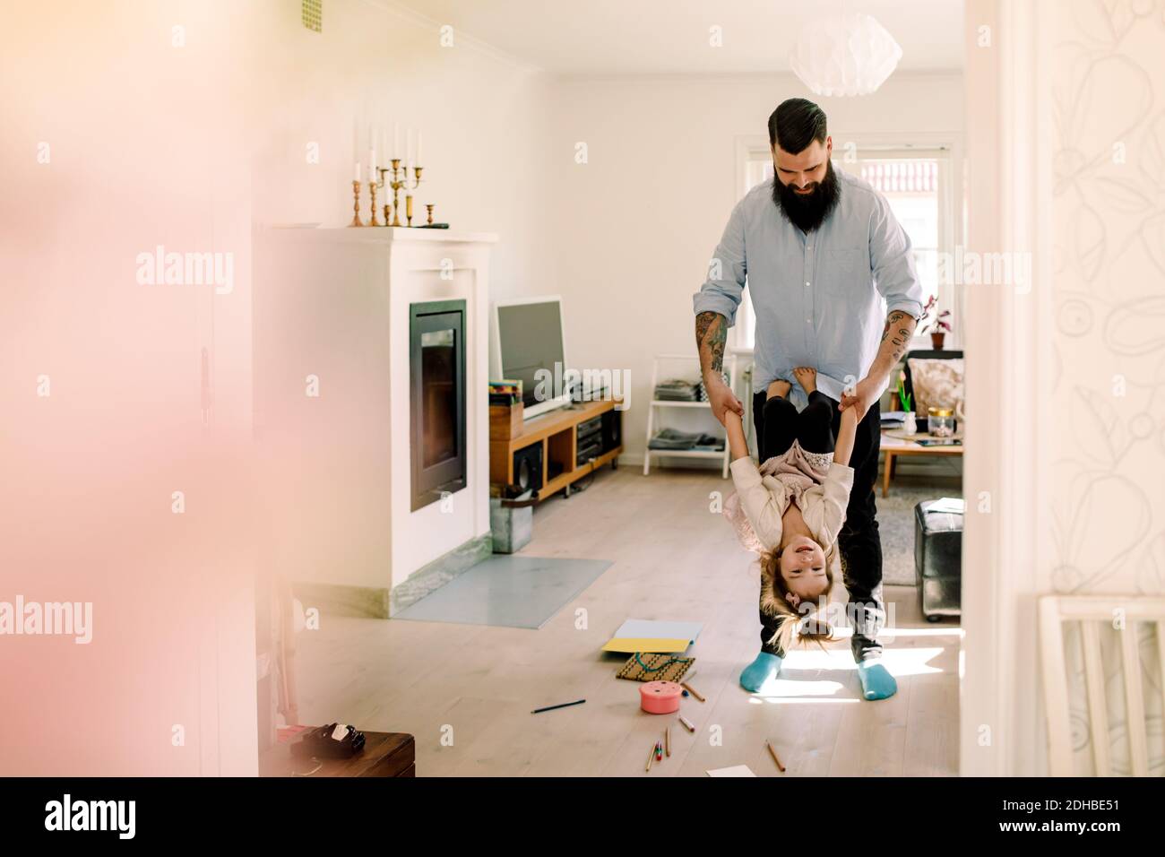 Mid adult father swinging cheerful daughter in living room at home Stock Photo