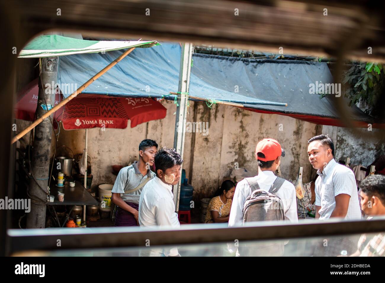 Yangon, Myanmar - December 31, 2019: Four local burmese men having a discussion outside a window of the traditional circle train in Yangon Stock Photo