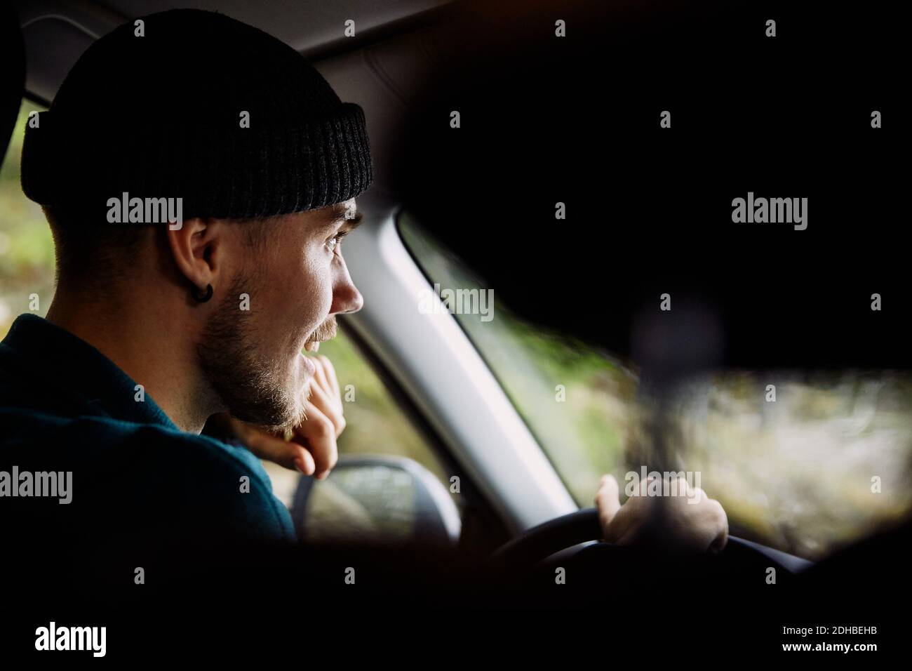 Smiling young man wearing knit hat while driving car Stock Photo