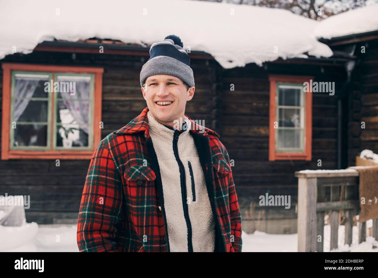 Smiling man standing against log cabin during winter Stock Photo