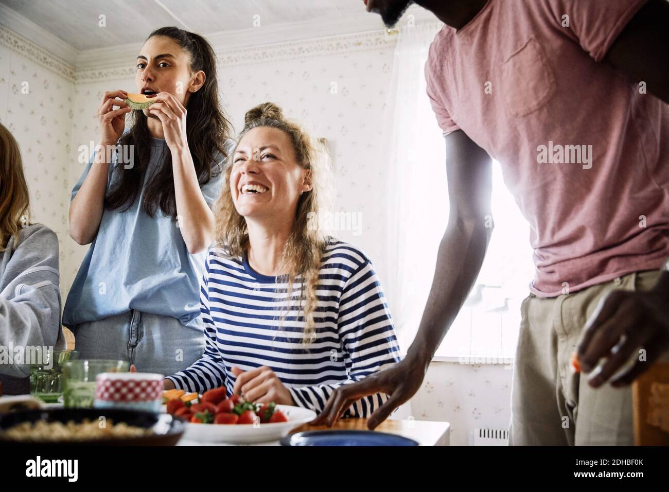 Low angle view of happy friends enjoying food in social gathering at home Stock Photo