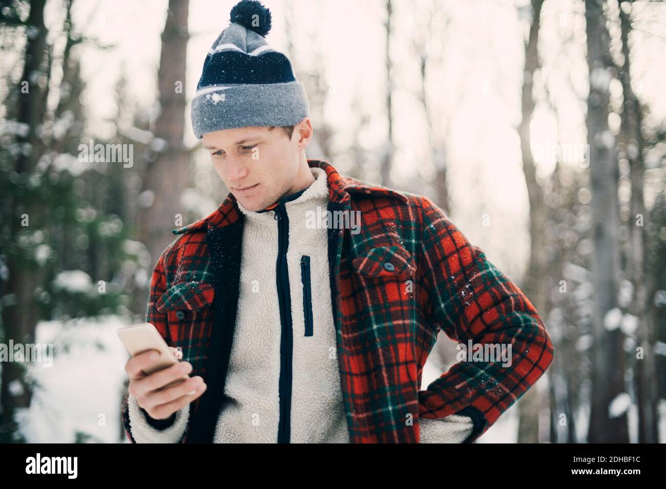 Man using smart phone while standing at park during winter Stock Photo