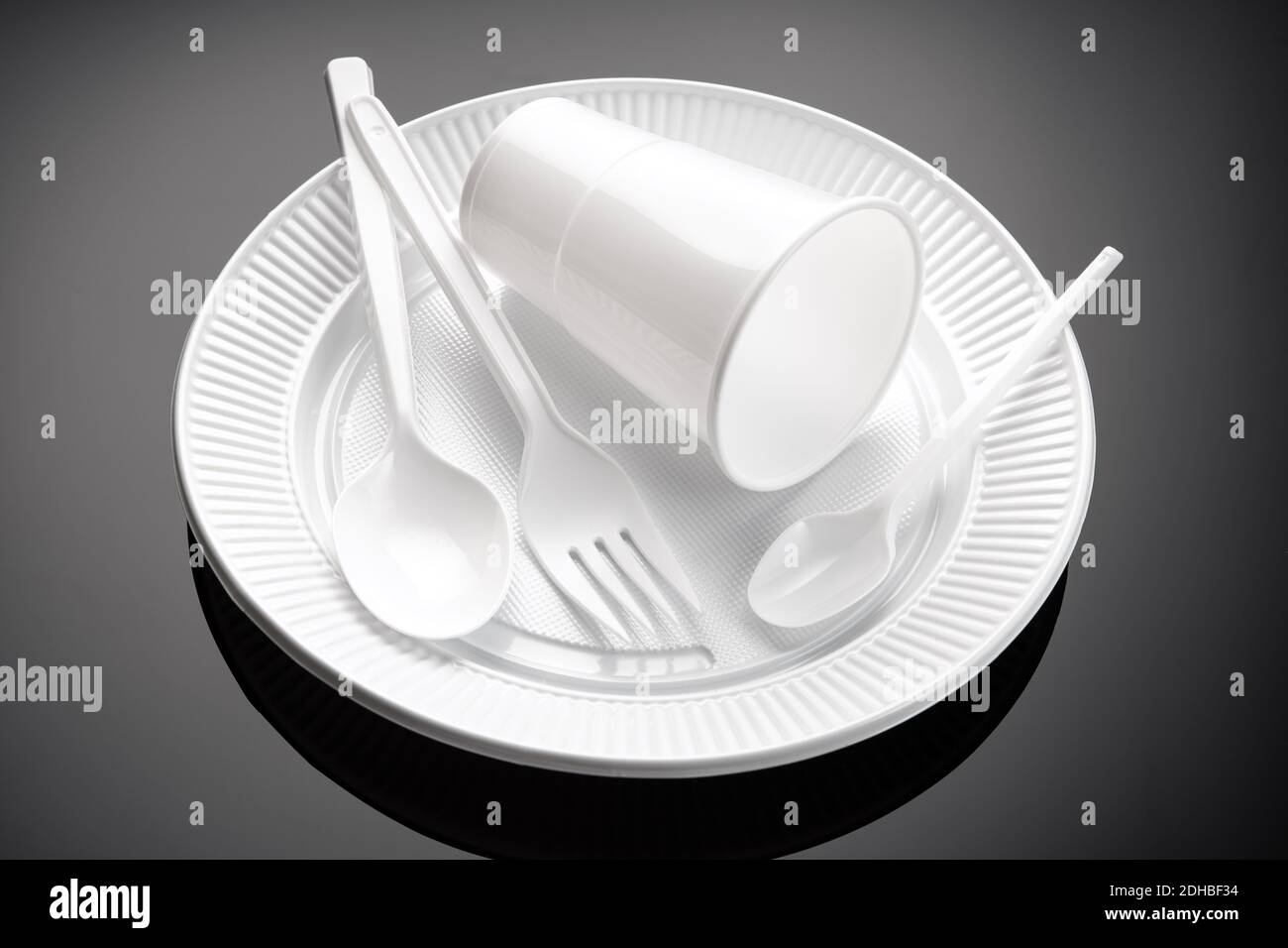 Plastic dishware. White cup, plate, fork and spoon Disposable plastic waste Stock Photo