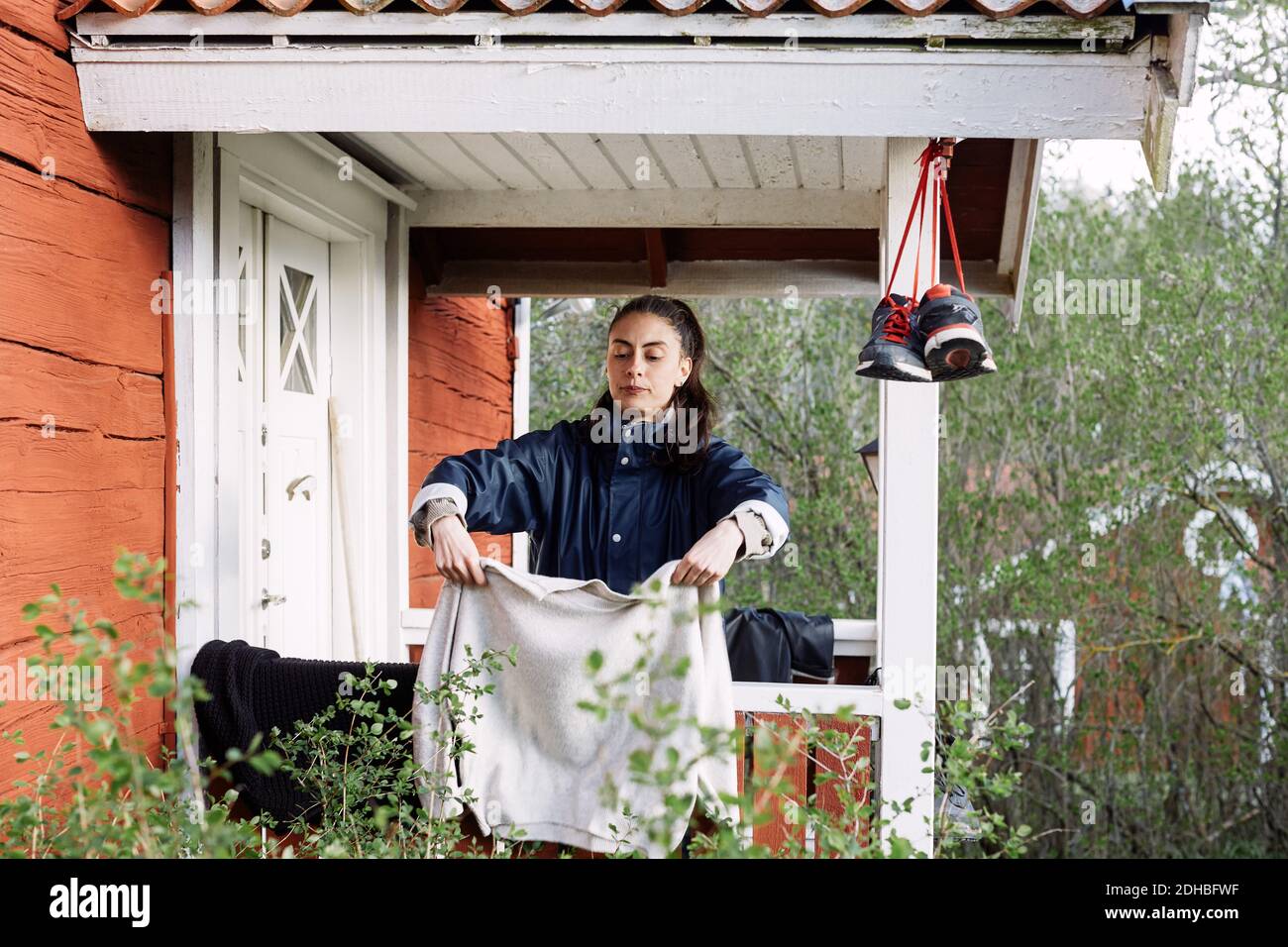 Young woman drying clothes while standing outside cottage Stock Photo
