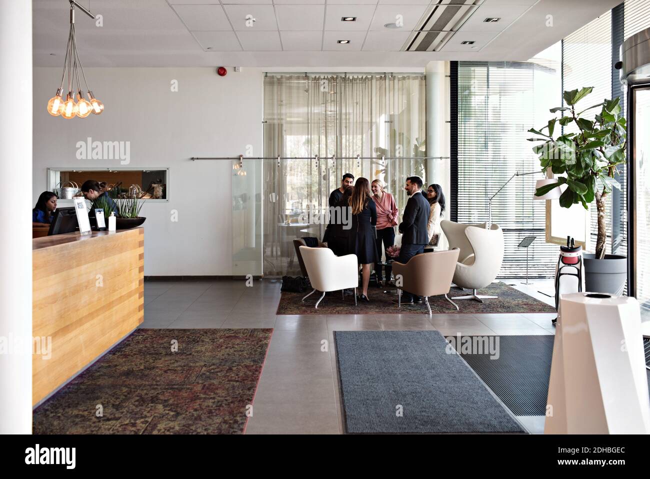 Business people talking while standing in lobby at office Stock Photo