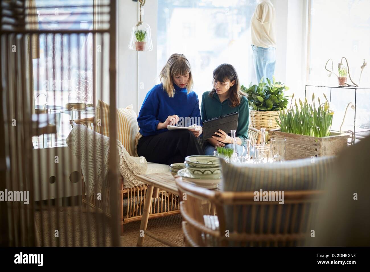 Female partners looking at notepad while discussing at boutique Stock Photo