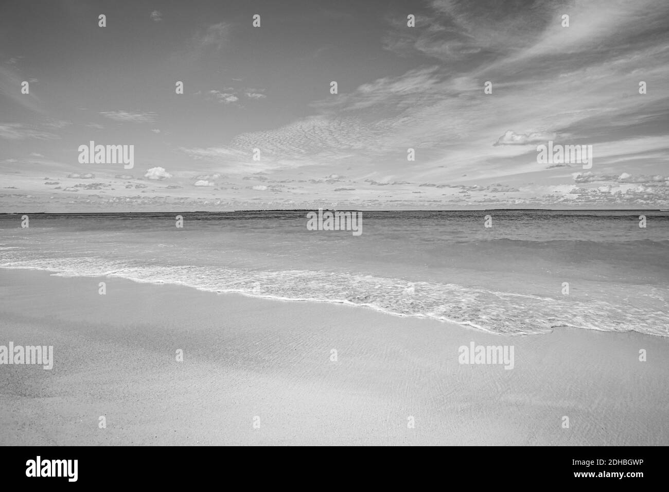 Wave and sandy beach in black and white. Calm view during sunset at seaside. Calm waves splashing sea horizon and dramatic mood Stock Photo