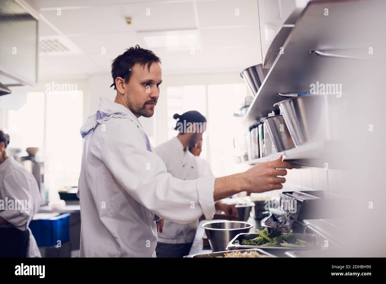 Young male chef reading order ticket in commercial kitchen Stock Photo