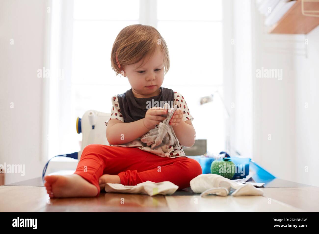 Full length of girl playing while sitting on table at home Stock Photo