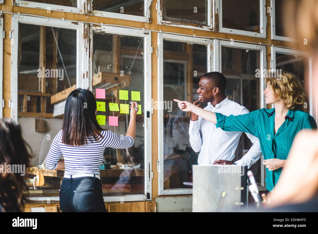 Confident computer programmers using adhesive notes to pen down their innovative ideas during meeting at workplace Stock Photo