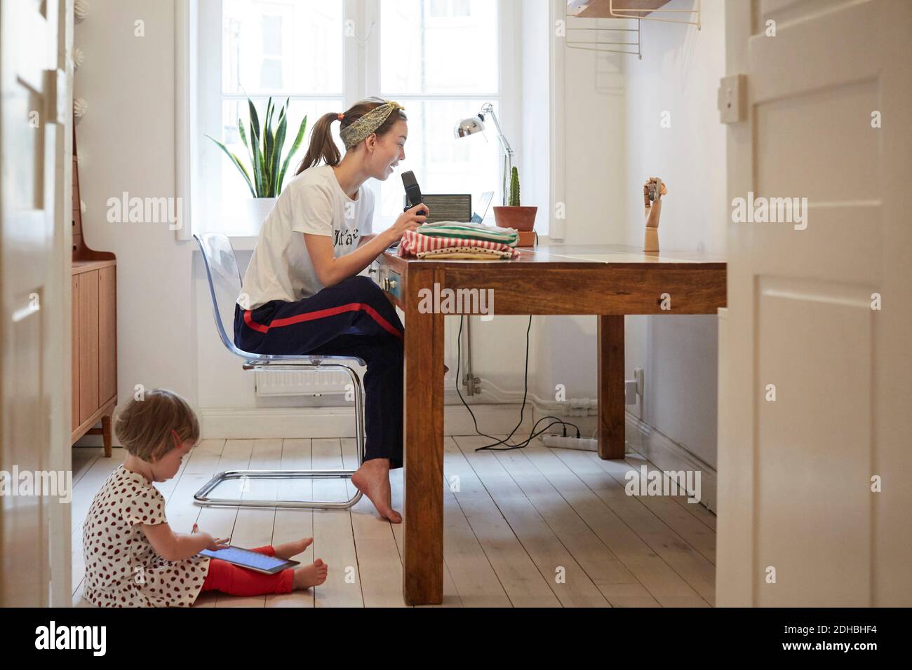 Podcaster talking on microphone while daughter using digital tablet at home Stock Photo