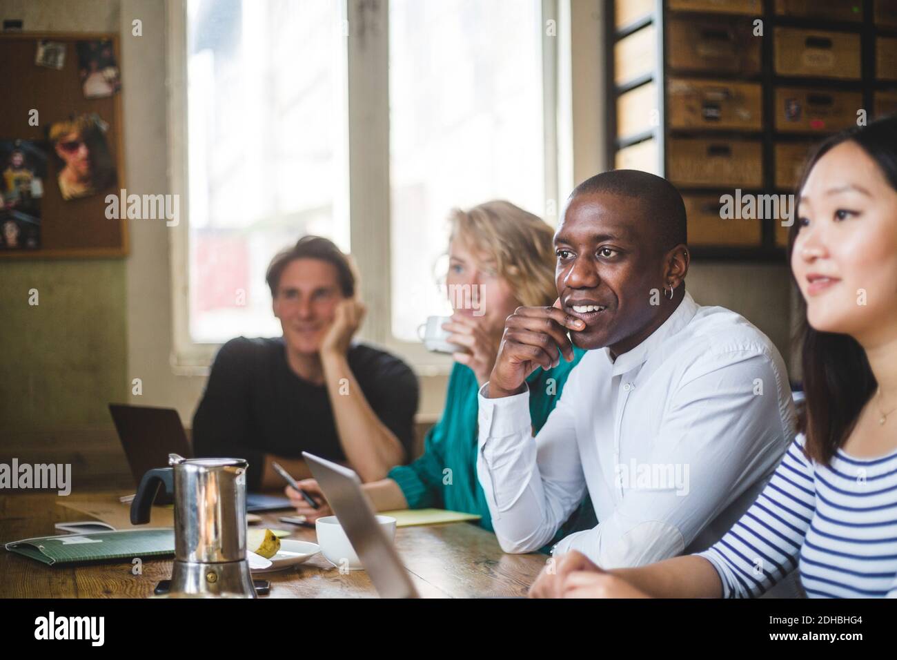 Confident young IT experts looking away while sitting at desk in creative workplace Stock Photo