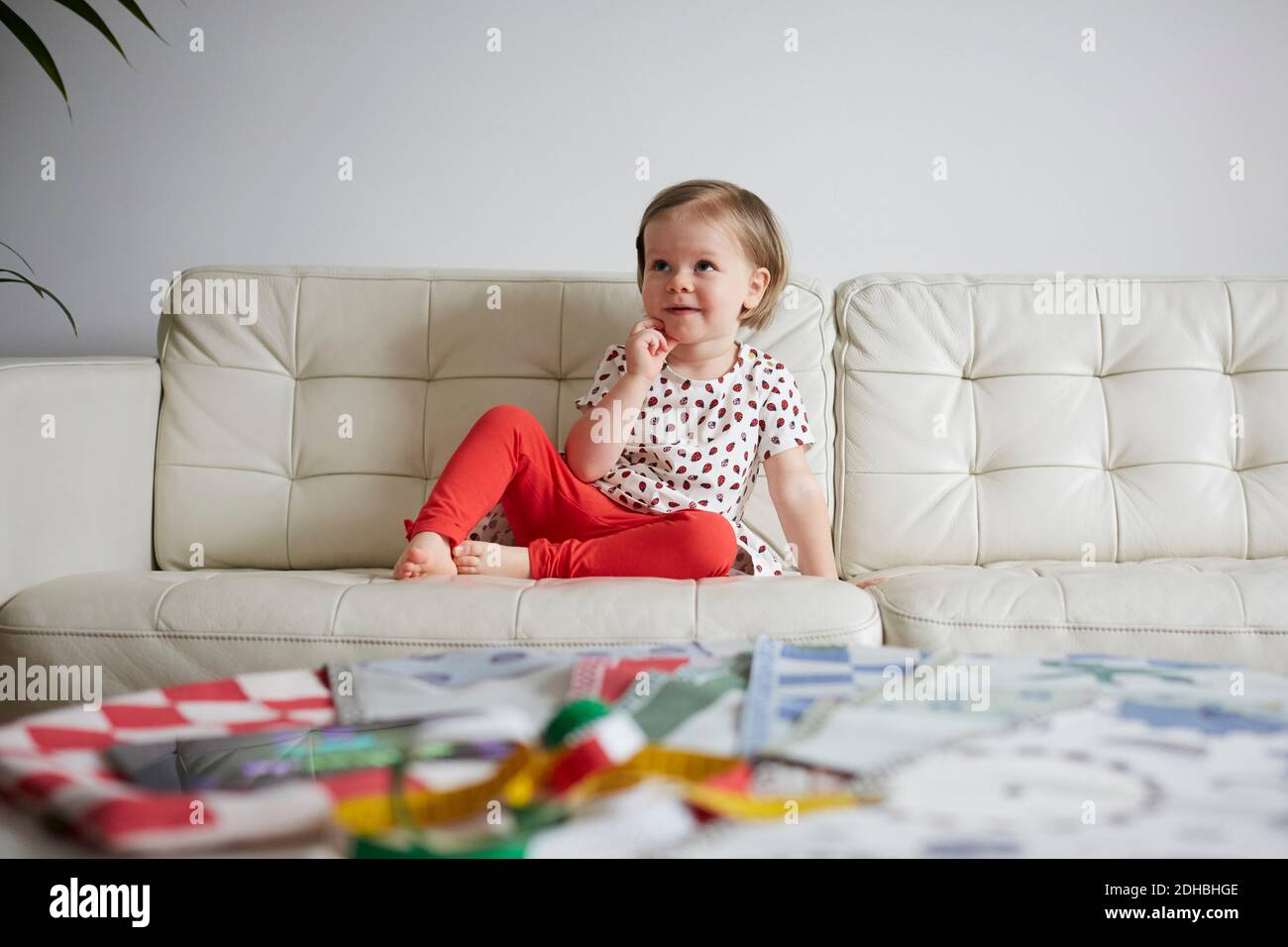 Thoughtful girl sitting on sofa at home Stock Photo