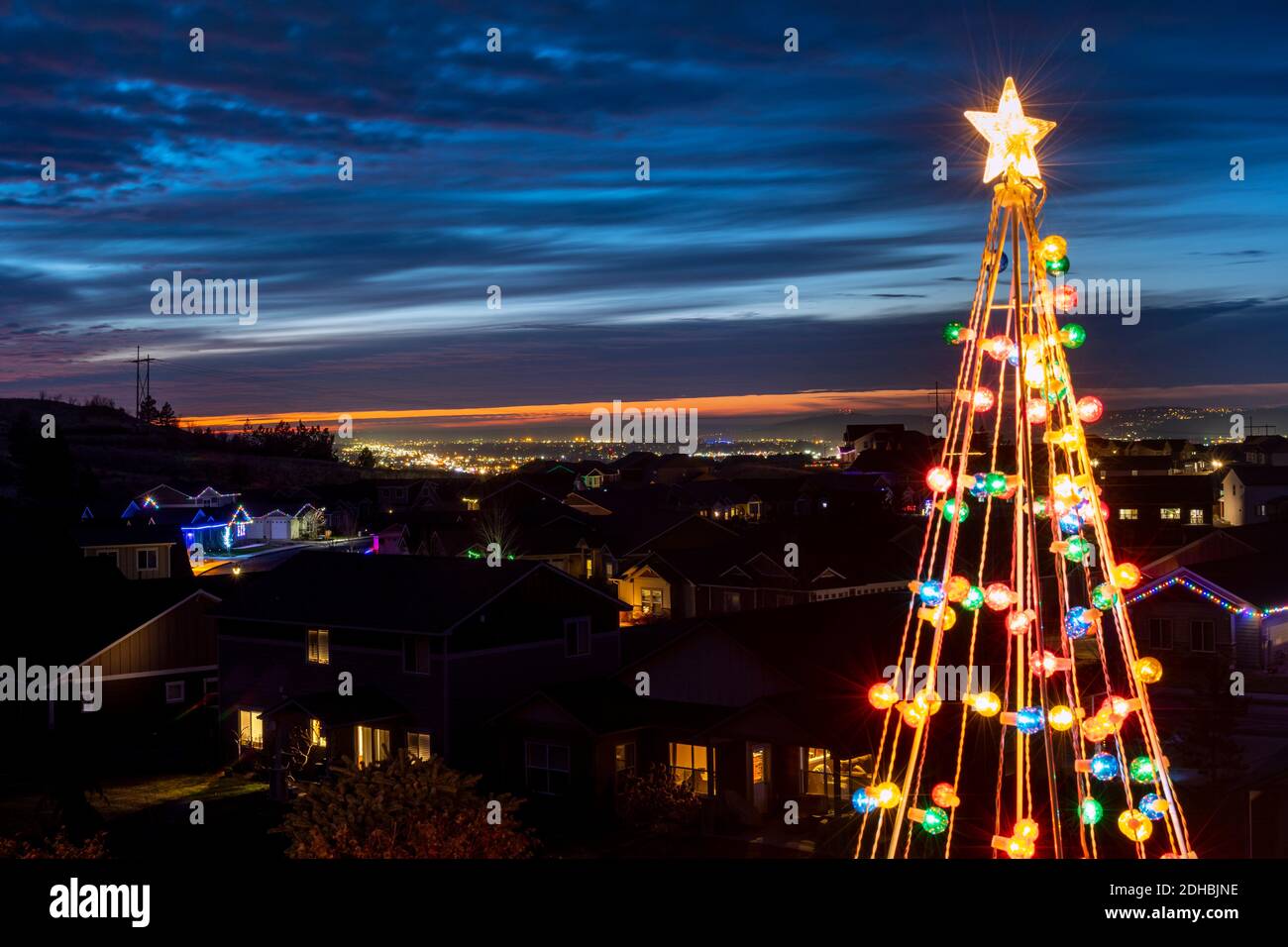 A lighted illuminated artificial Christmas holiday tree with an illuminated city and valley