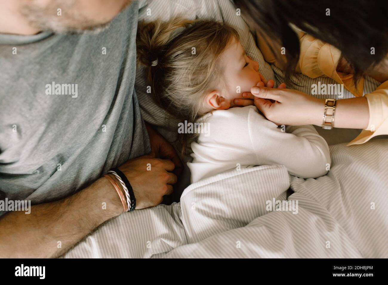 Directly above shot of girl sleeping with parents in bed at hotel Stock Photo