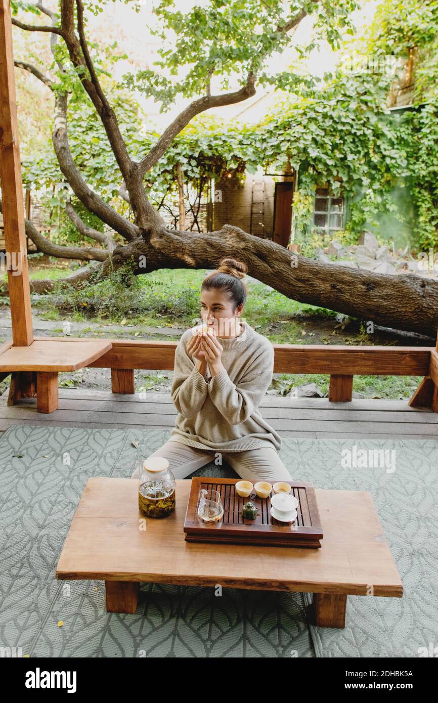Lovely woman with a cup of tea sitting on floor during traditional chinese tea ceremony. Stock Photo