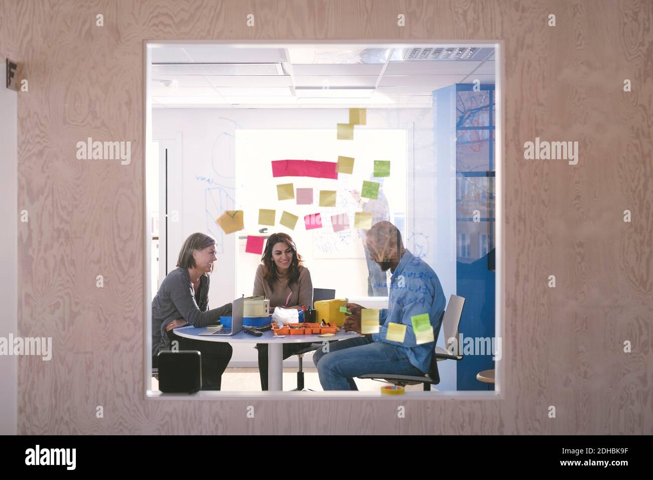Adhesive notes stuck on glass with business professionals working in background Stock Photo
