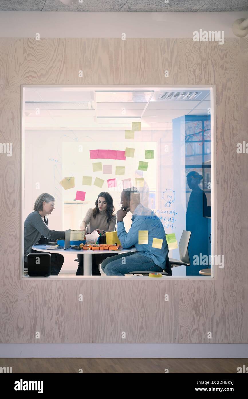 Adhesive notes stuck on glass with engineers working in background Stock Photo