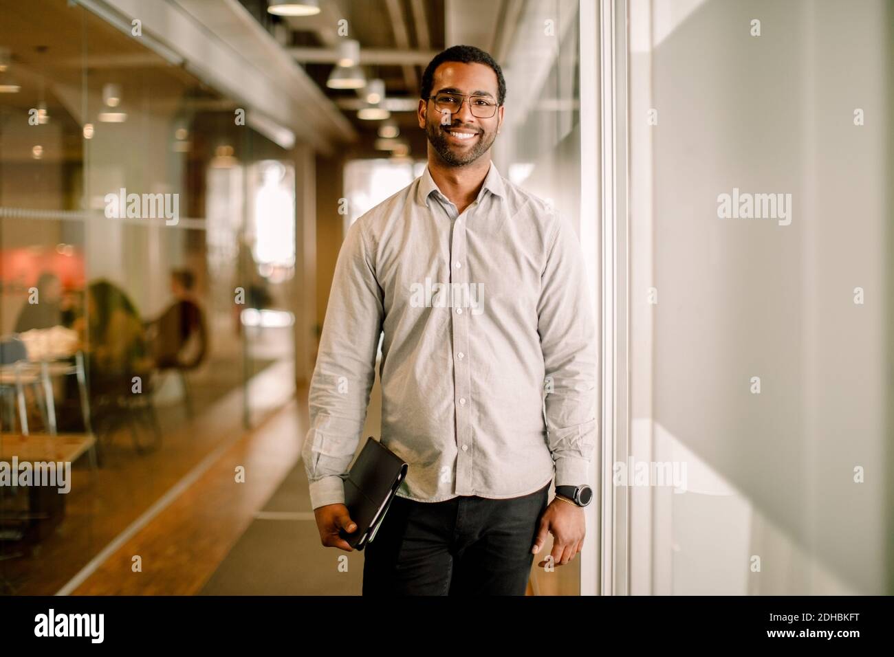 Portrait of smiling sales executive standing in corridor at work place Stock Photo