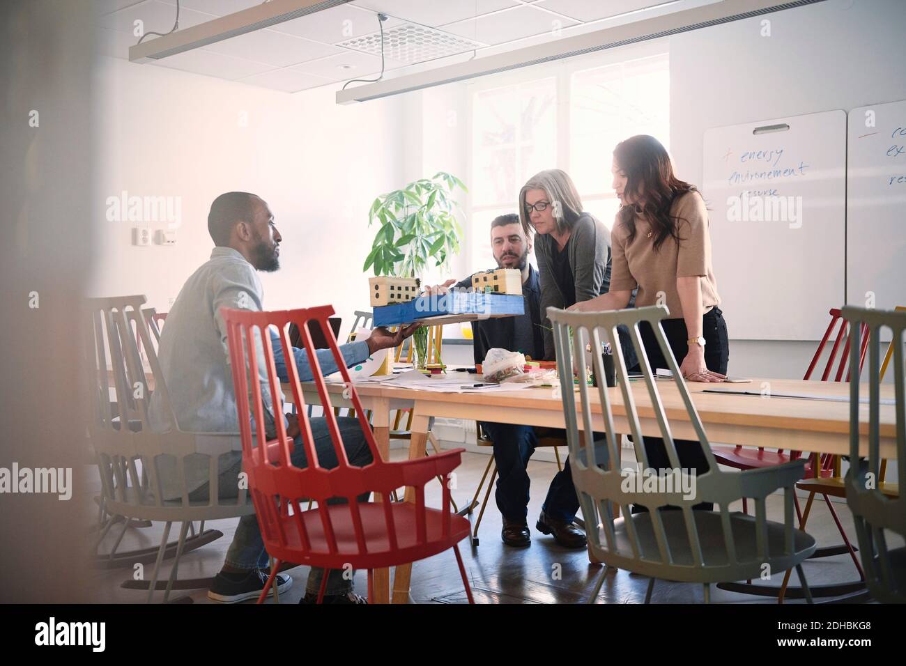 Male engineer showing architectural model to colleagues at table during meeting in office Stock Photo