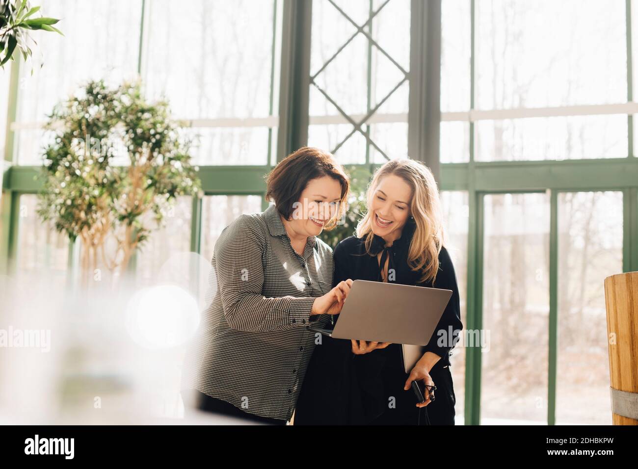 Happy business colleagues discussing over laptop at office Stock Photo