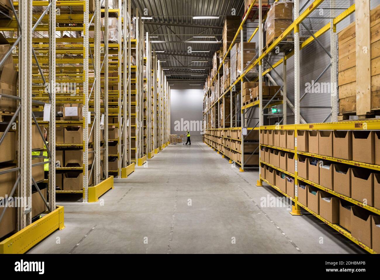 Aisle amidst packages on racks at illuminated distribution warehouse Stock Photo