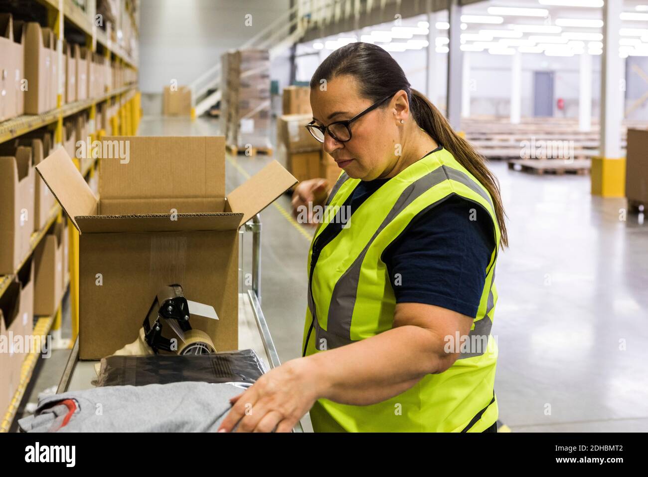 Side view of female worker packing cardboard box at warehouse Stock ...