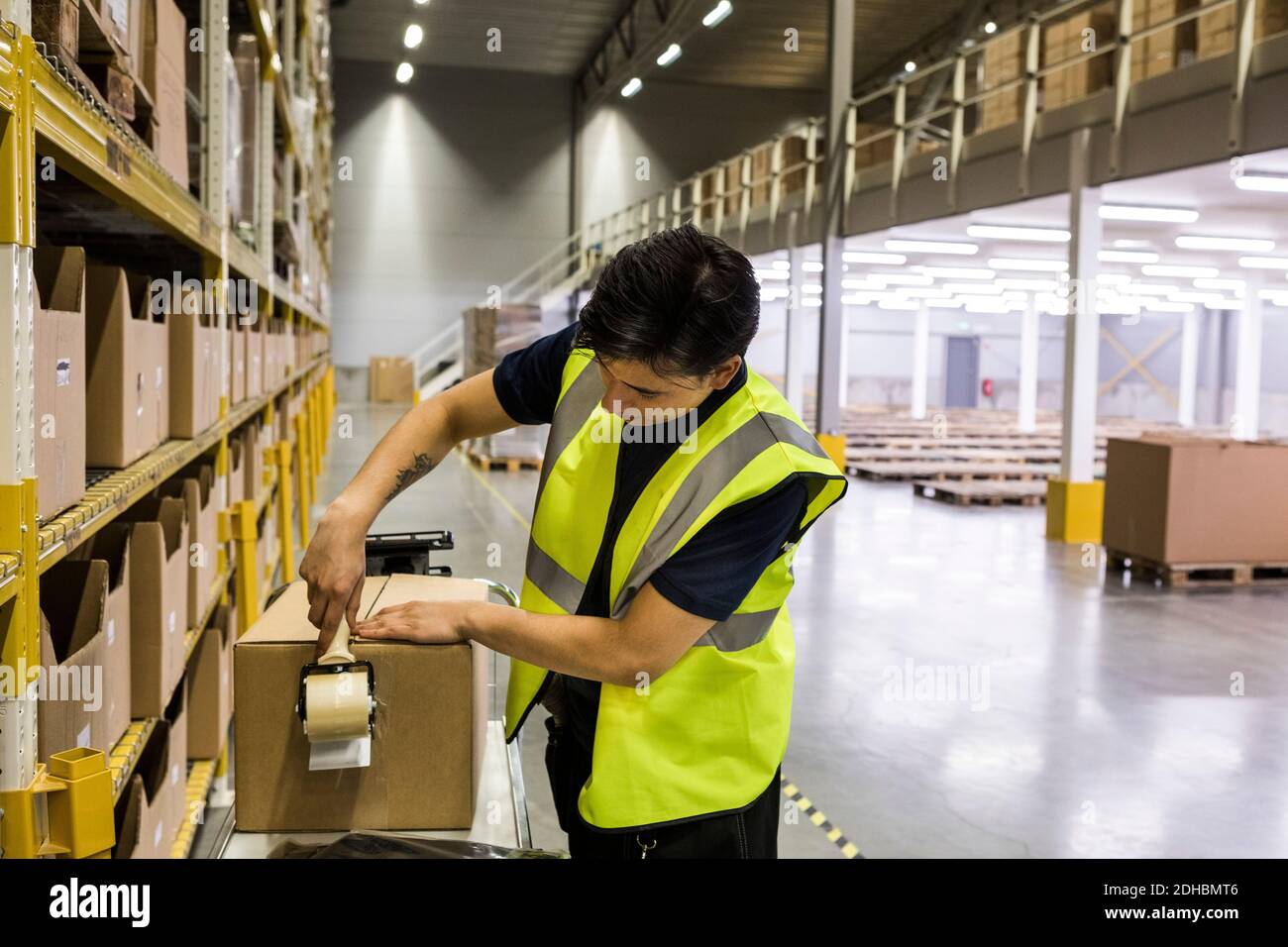 Young male worker packing cardboard box with adhesive tape at ...