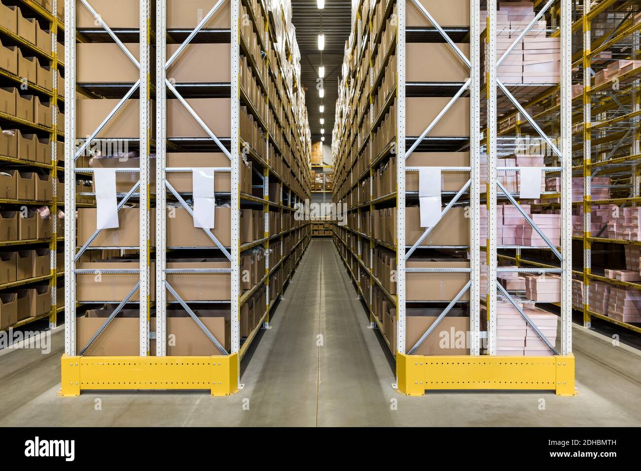Empty narrow aisle amidst racks at distribution warehouse Stock Photo