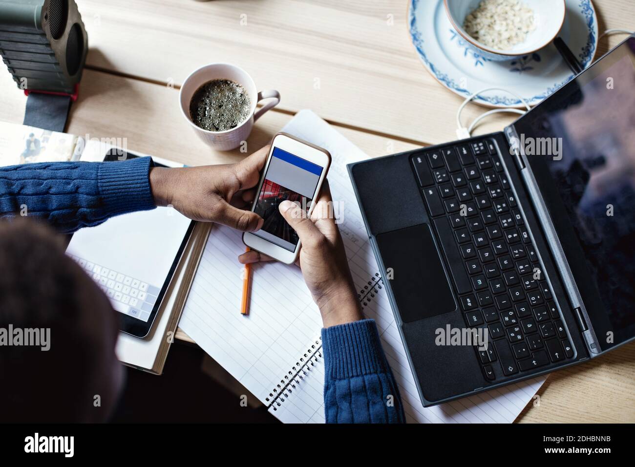 High angle view of teenage boy using mobile phone while studying on table at home Stock Photo