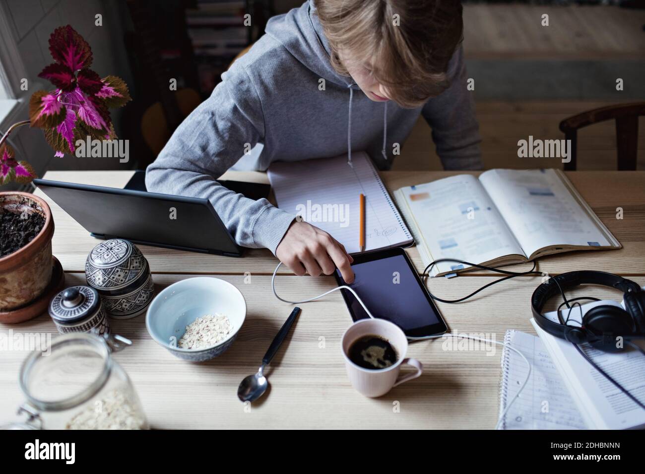 High angle view of teenage boy using digital tablet while studying on table at home Stock Photo