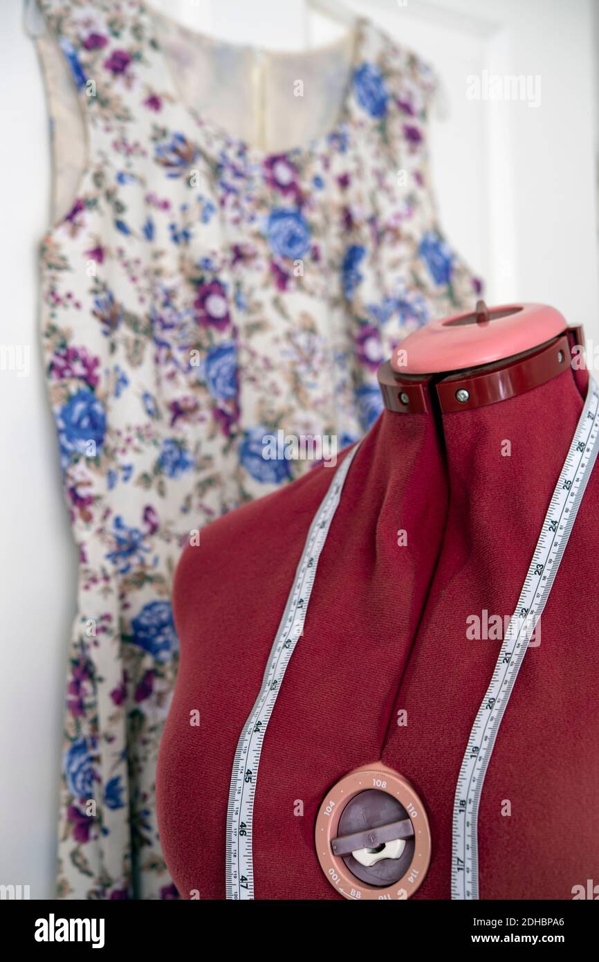 Dress form and tape measure with dress hanging behind Stock Photo Alamy