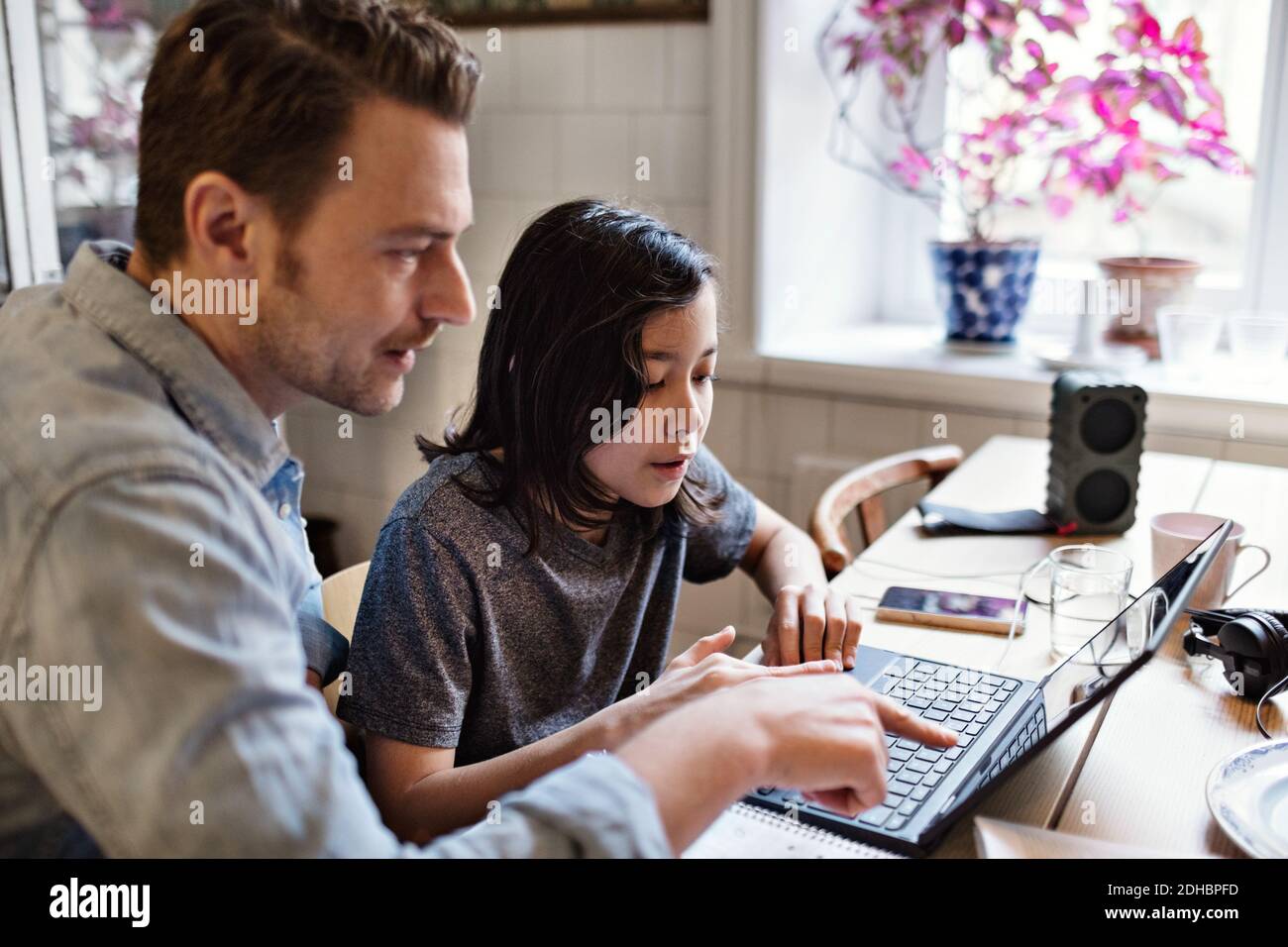 Father pointing at laptop while helping son in doing homework Stock Photo
