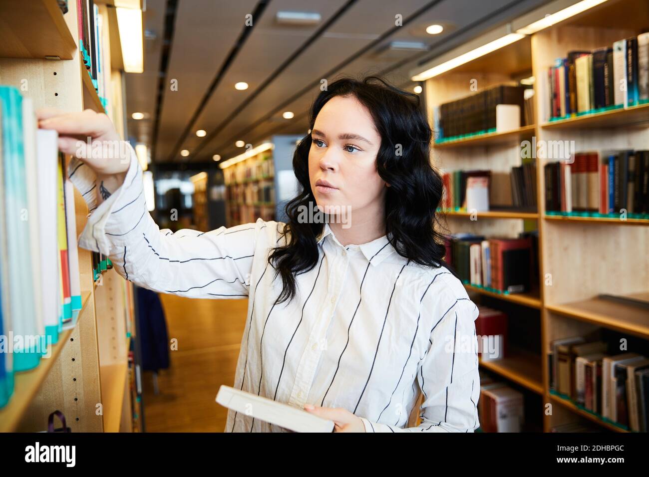 Young female student searching book in university library Stock Photo