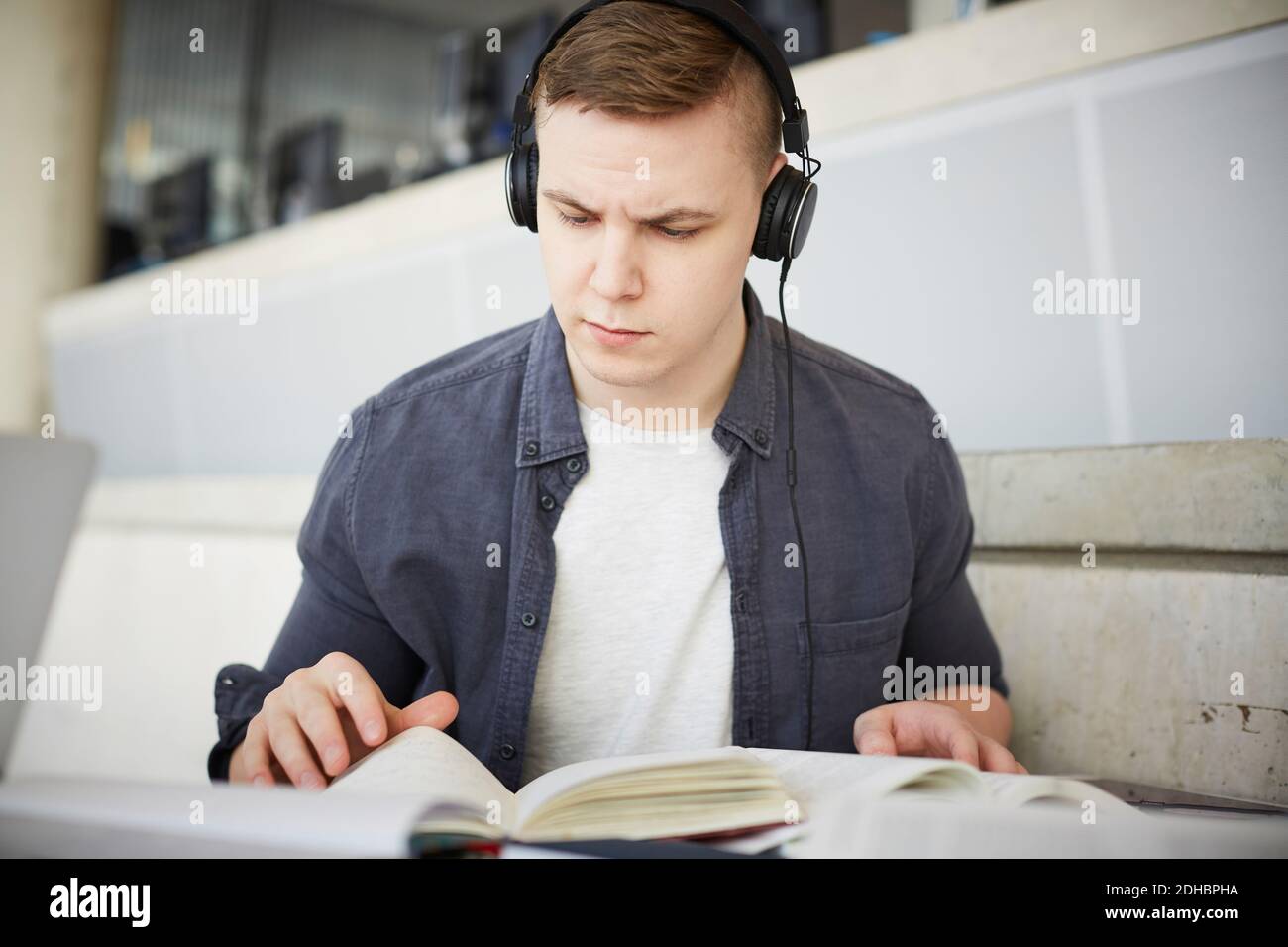 Young student wearing headphones while studying at table in university Stock Photo