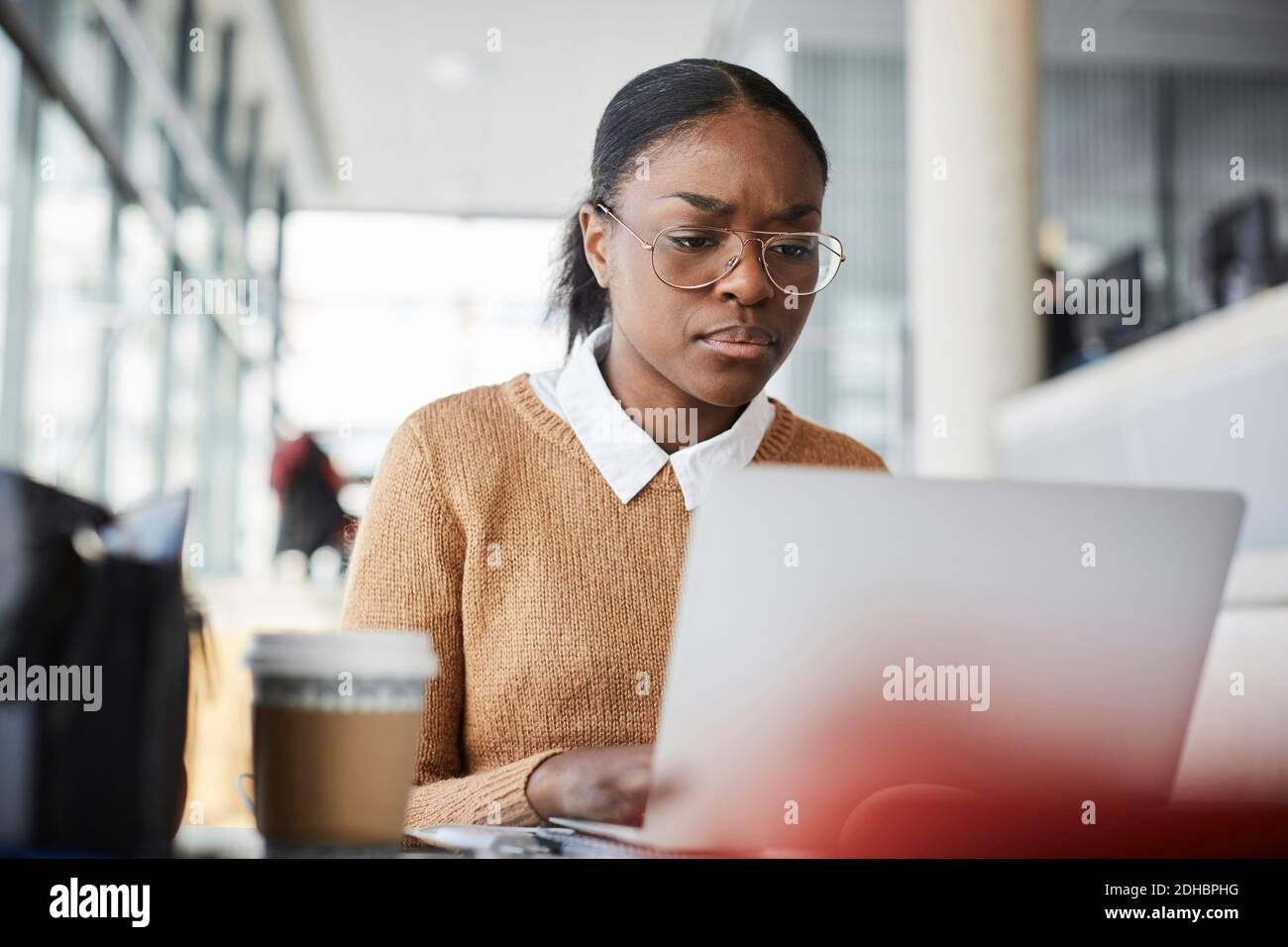 Serious young student using laptop while studying in university cafeteria Stock Photo