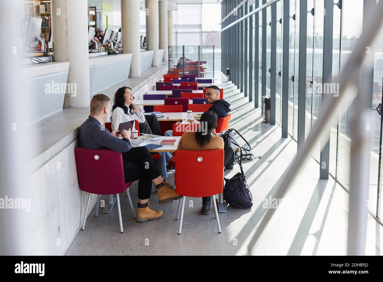 Friends talking while studying together at university cafeteria Stock Photo