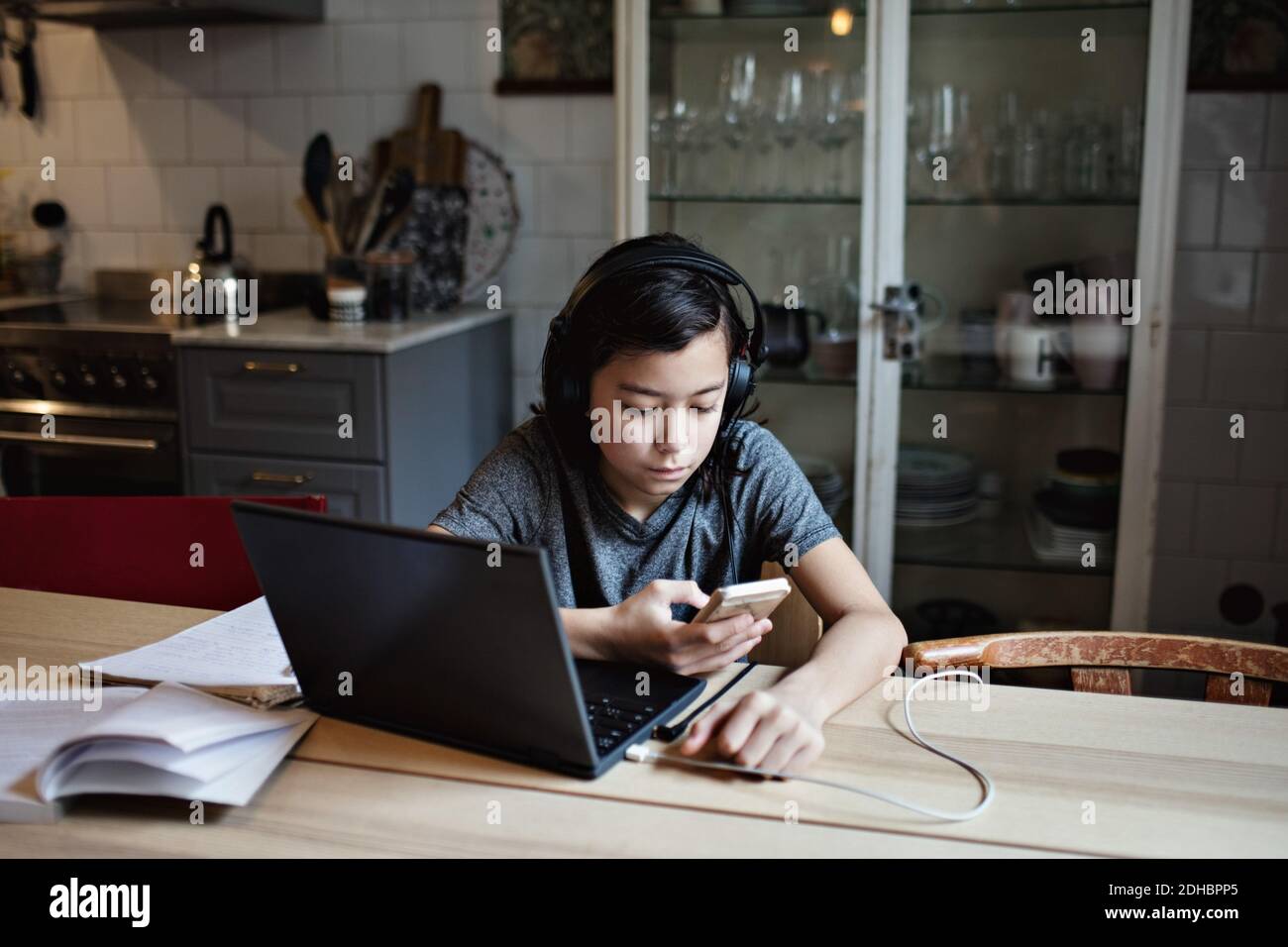 Boy using mobile phone for homework at home Stock Photo