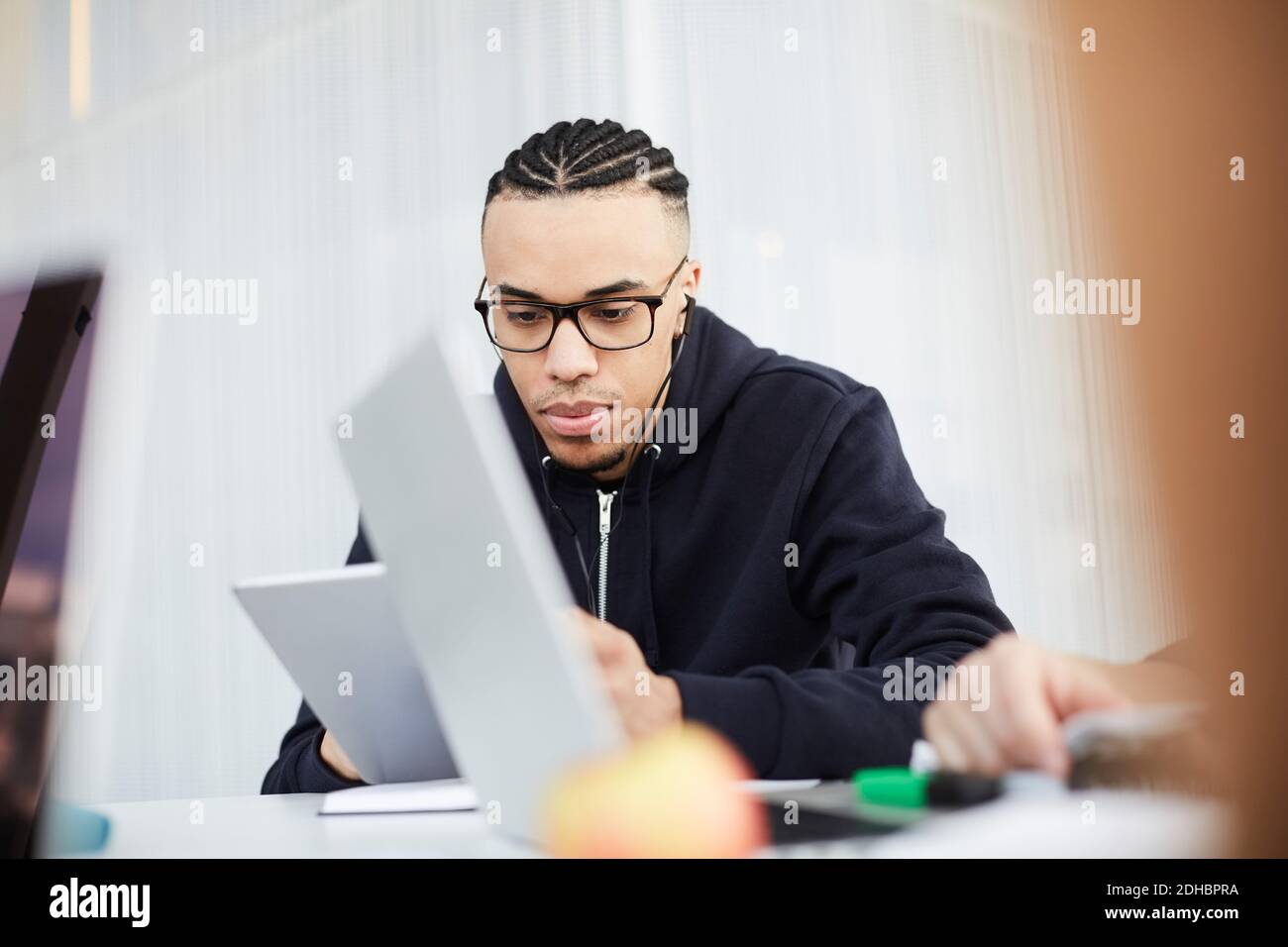 Young student using digital tablet while studying at table in university cafeteria Stock Photo