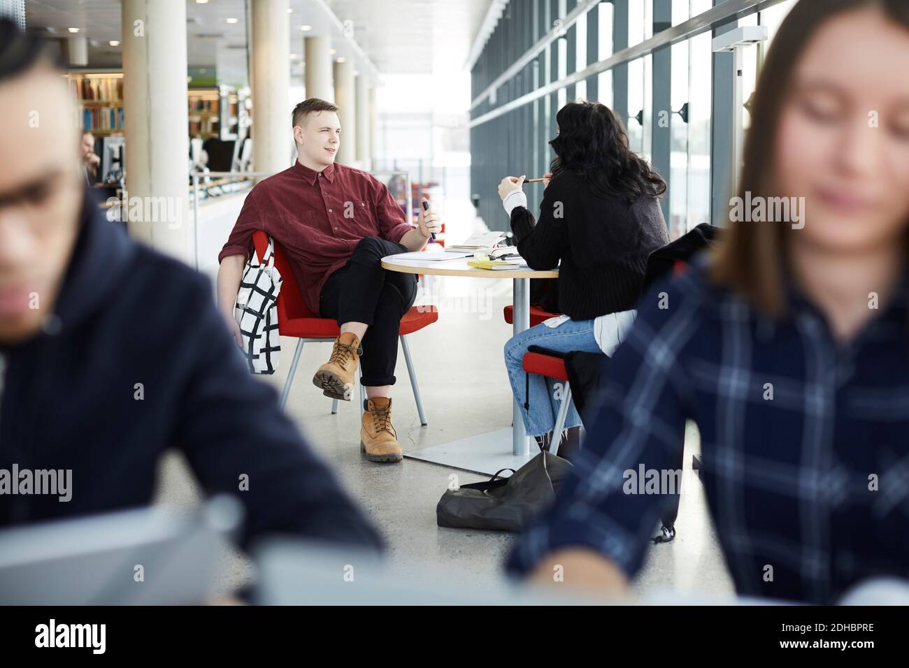 Friends talking while studying together at table in university cafeteria Stock Photo