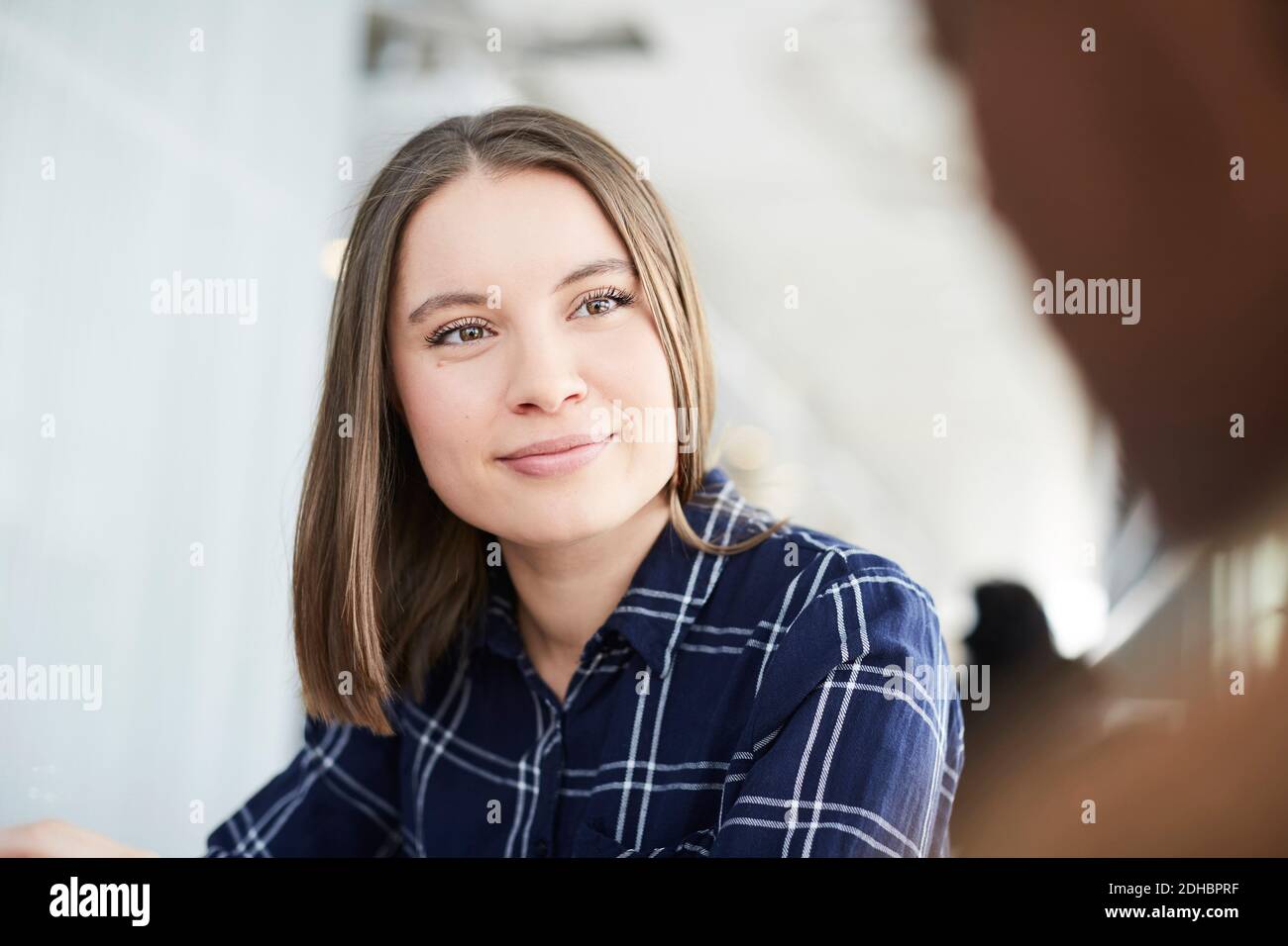 Young student looking at friend while sitting in cafeteria Stock Photo