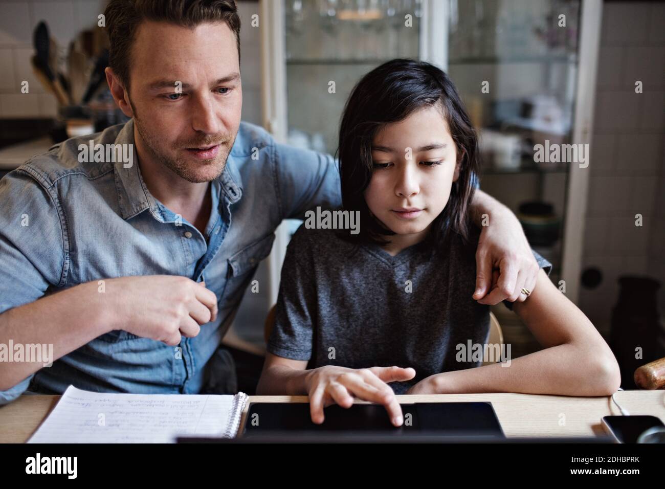 Son using laptop by father while doing homework at home Stock Photo