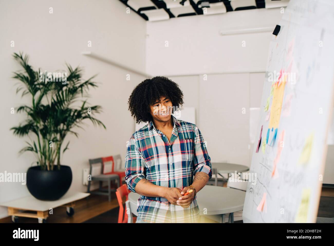 Smiling mid adult businessman looking at waste management strategy on whiteboard at creative office Stock Photo
