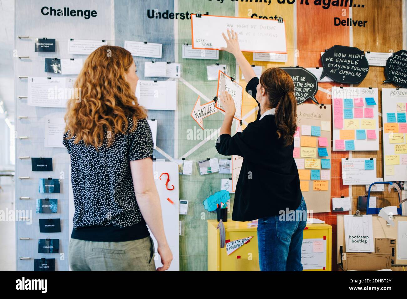 Female colleagues discussing over strategy on wall at creative office Stock Photo