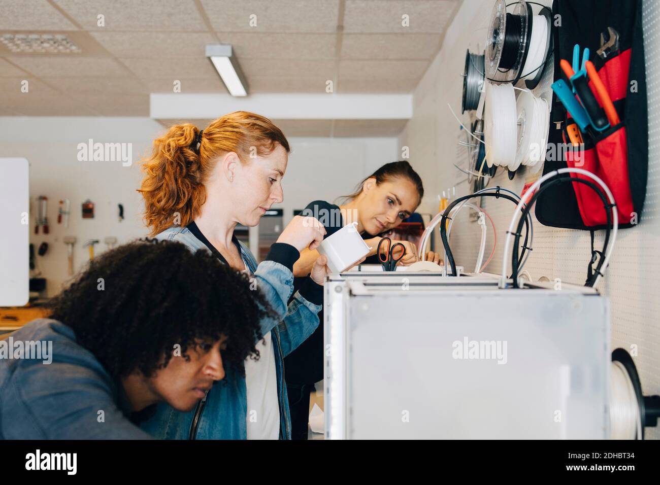 Multi-ethnic male and female engineers working on machinery at creative office Stock Photo